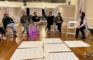 People in chairs and brainstorming suggestions written on large sheets of paper