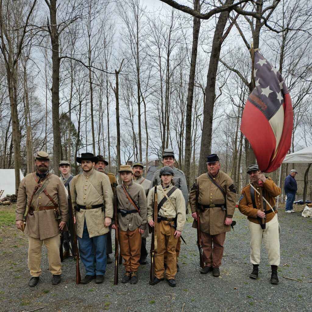 A group of men and boys dressed in Civil War garb and carrying old-style guns.