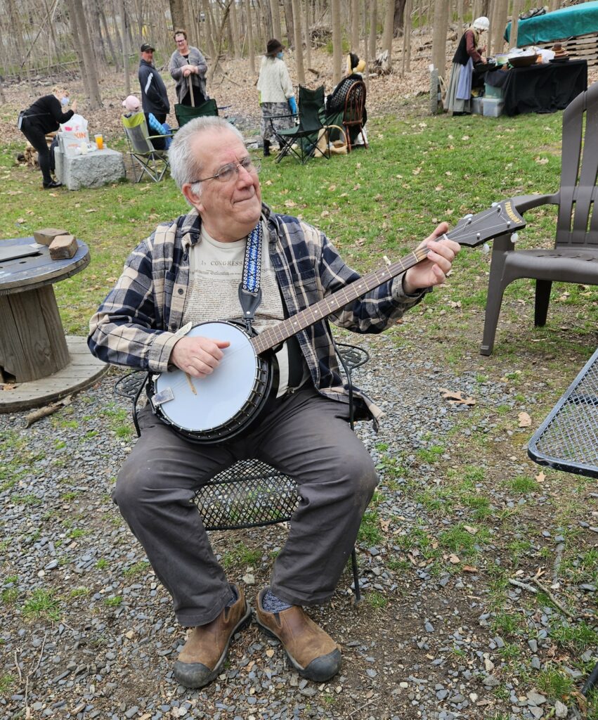 Seated man playing a 5-string banjo.