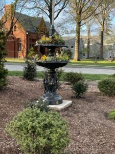 A Victorian-era cast zinc fountain planted with colorful flowers.