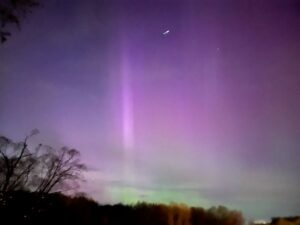 The sky with the northern lights in full bloom. The sky is purple and green with a few stars showing.