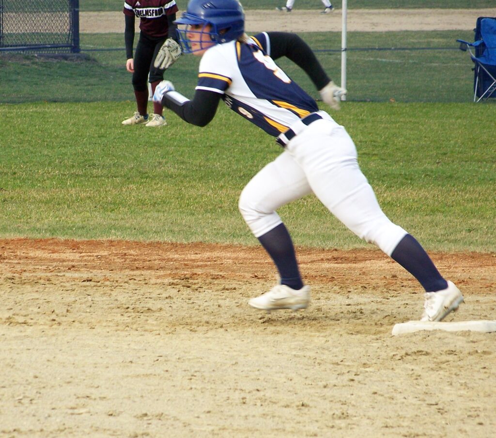 A Revs player leaves second base, heading towards third.