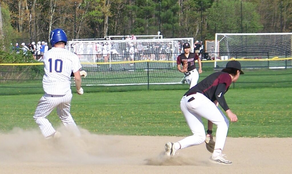 A Revs player runs in the dust. Two players in black and maroon chase the ball.