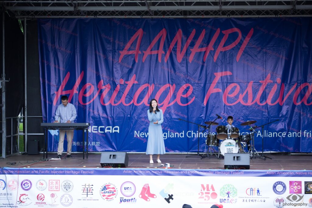 Three performers on stage. The backgdrop says AANHPI Heritage Festival in large letters.