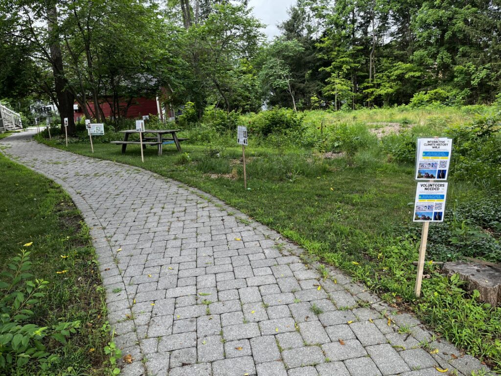 The path to the Red House. On one side, posters are nailed to wooden posts.