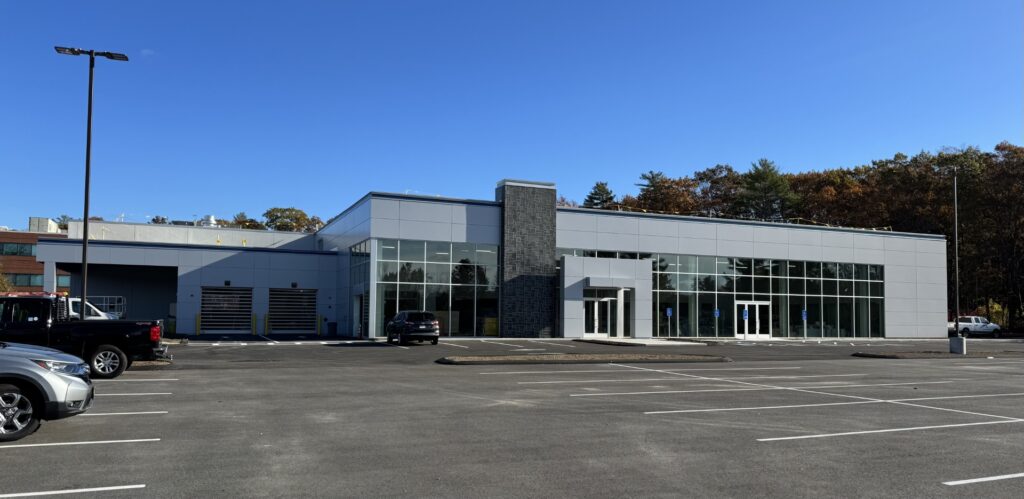 A large glass-fronted building in an empty parking lot. It does not yet have sign.