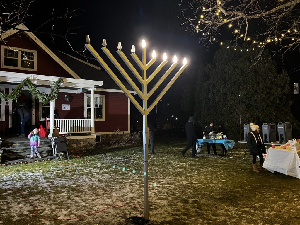 A tall electric menorah shines in the dark.