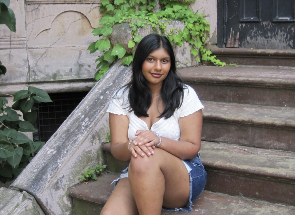 A young woman sits on cracked stone steps.