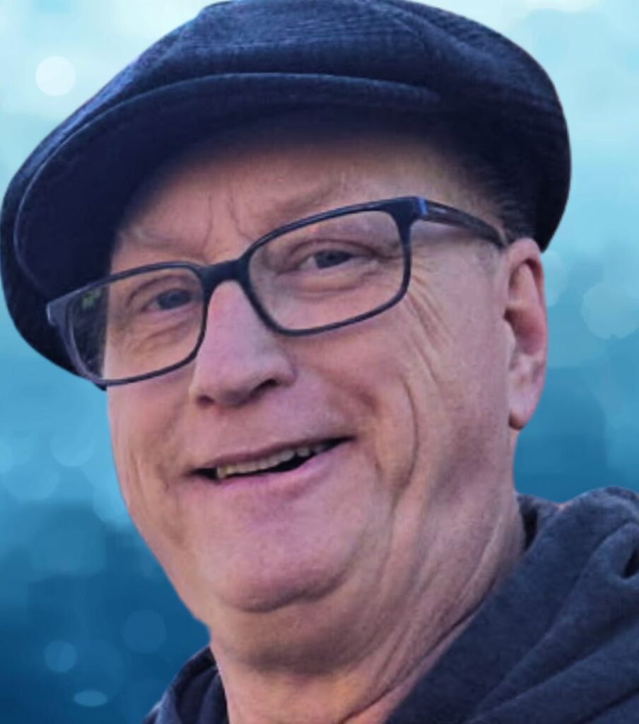 Smiling elderly man, wearing glasses and a cap.
