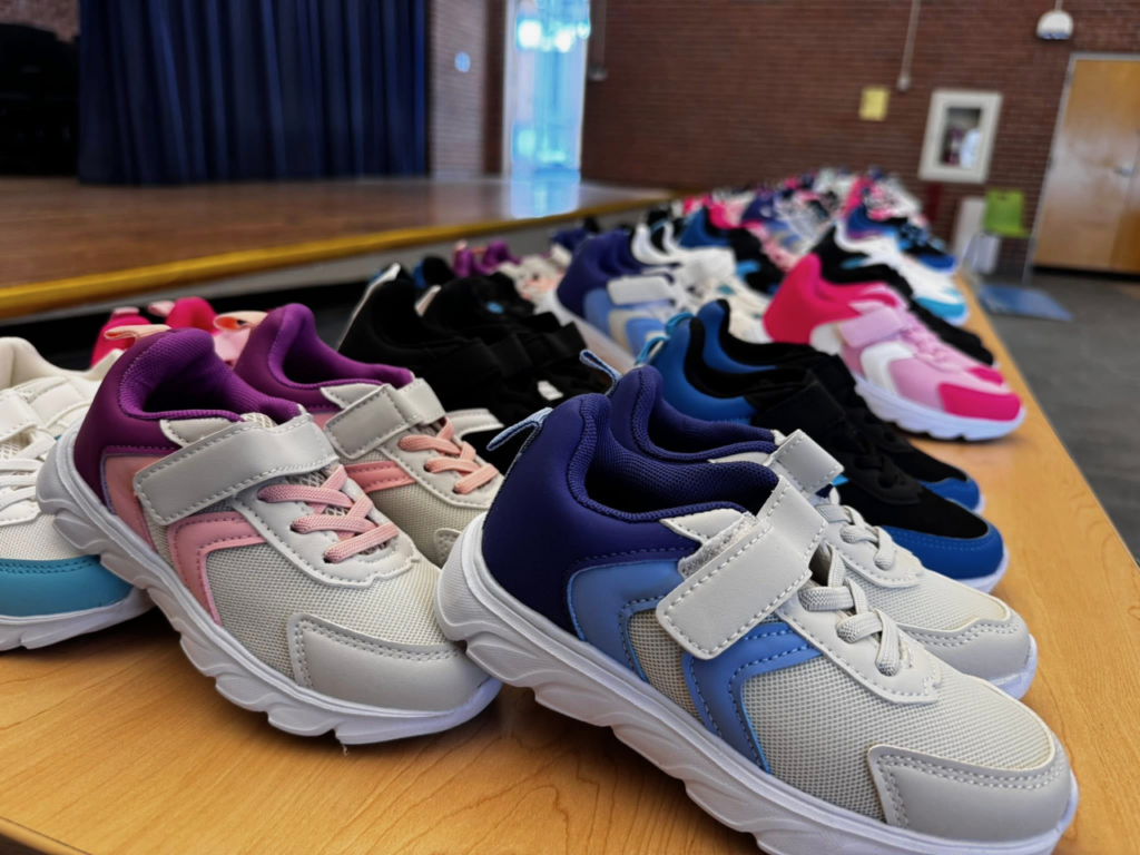 Photo of dozens and dozens of pairs of new sneakers, displayed neatly across the front of a stage.