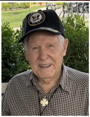 An older man wearing a US Navy cap (where he served during WWII).