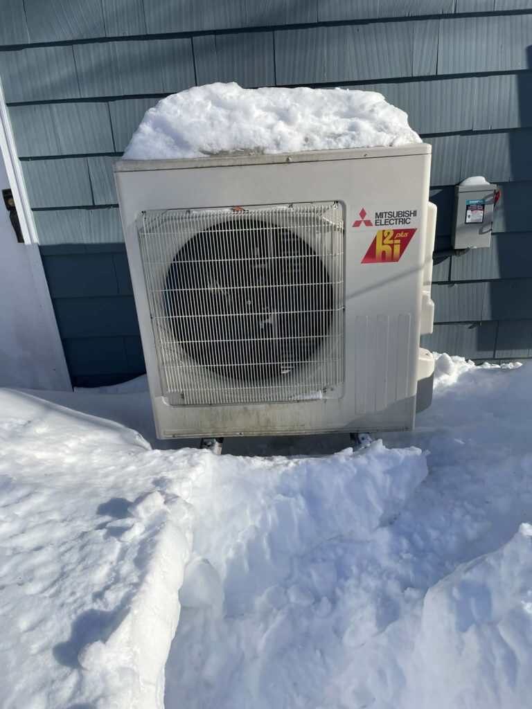 A square piece of machinery sits outside by the house. There is snow on the top (which is fine), but the snow has been cleared from the sides and bottom.