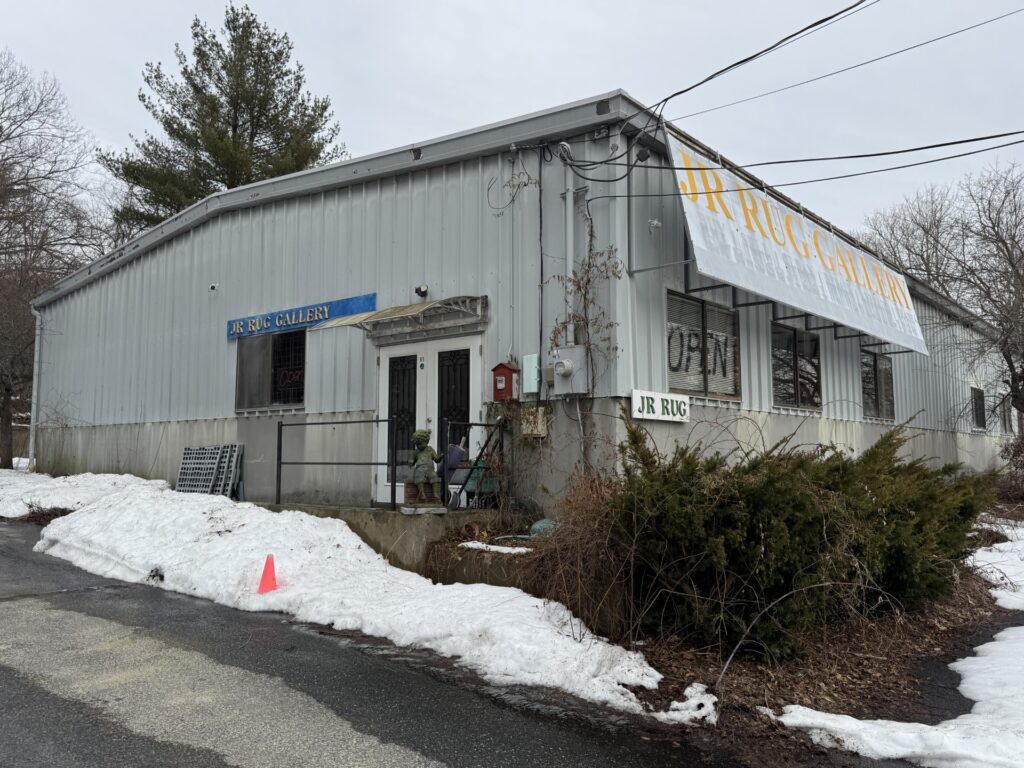 A metal sided building with signs that read JR Rug Gallery.