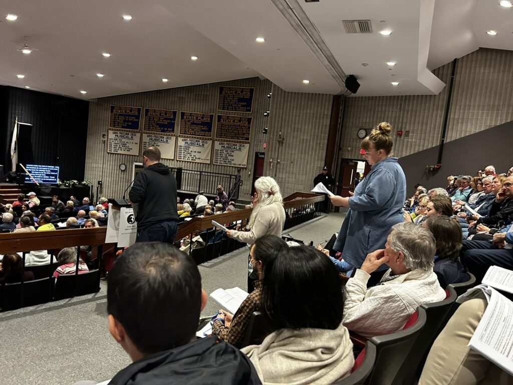People lined up in front of a microphone in the ABRHS auditorium.