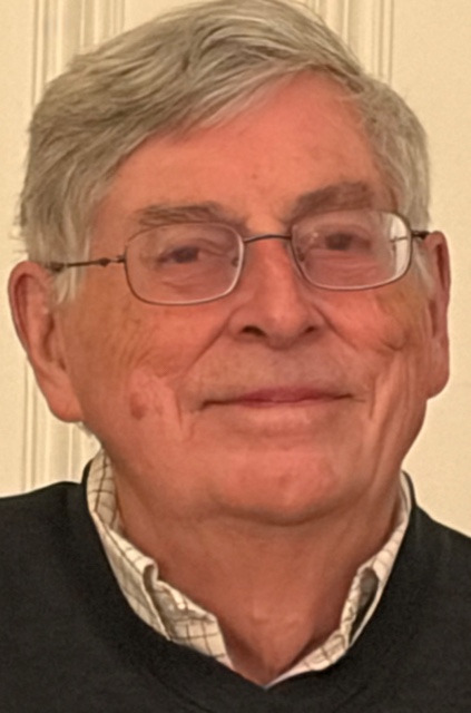 A smiling grey-hiared man with glasses,