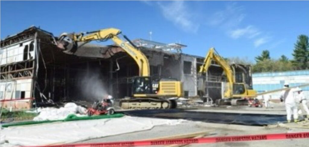 A building being demolished by a couple of excavators.