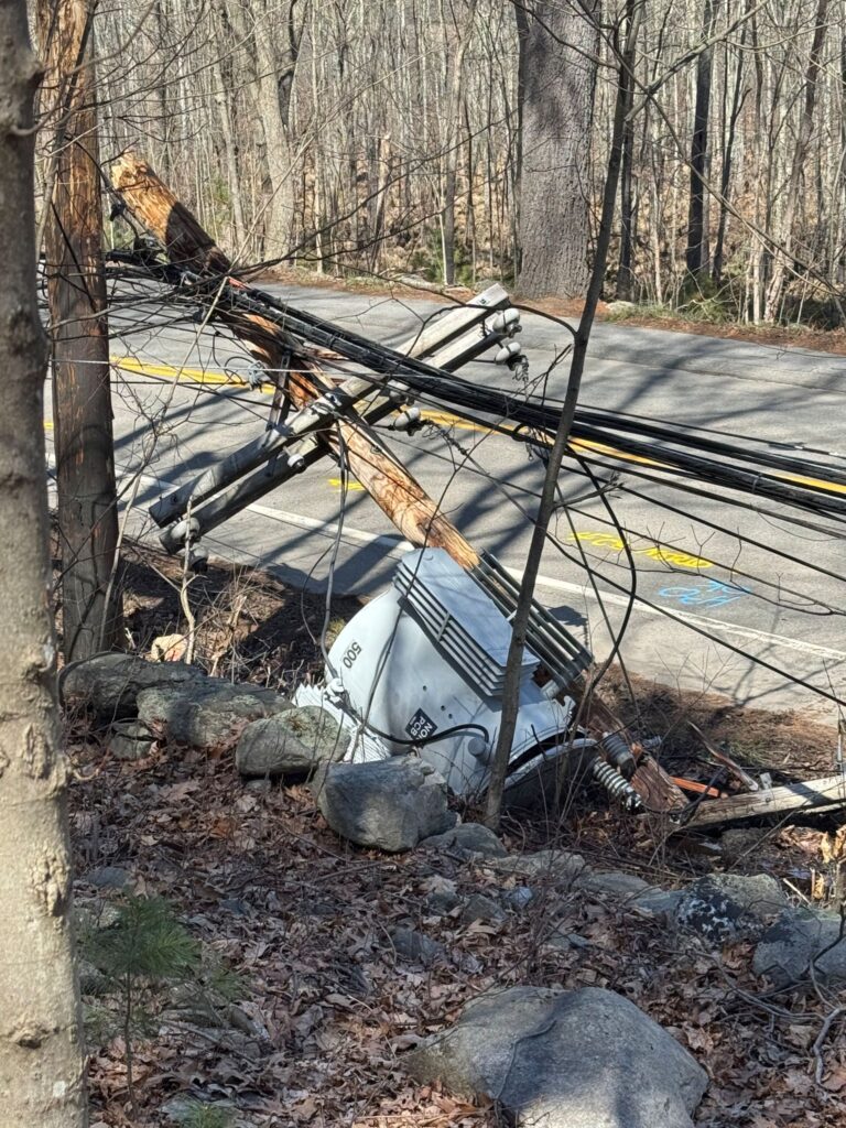A tranformeron the ground attached to a broken pole.