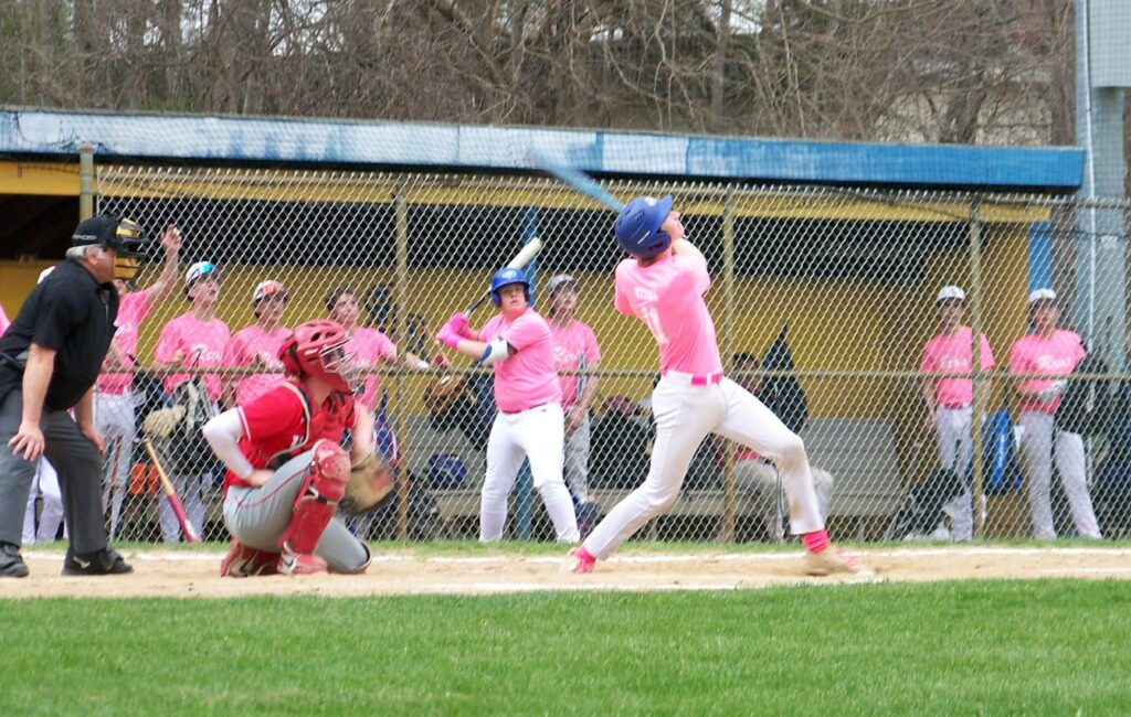 A baseball player at the end of a good swing. Several other players are in the background.