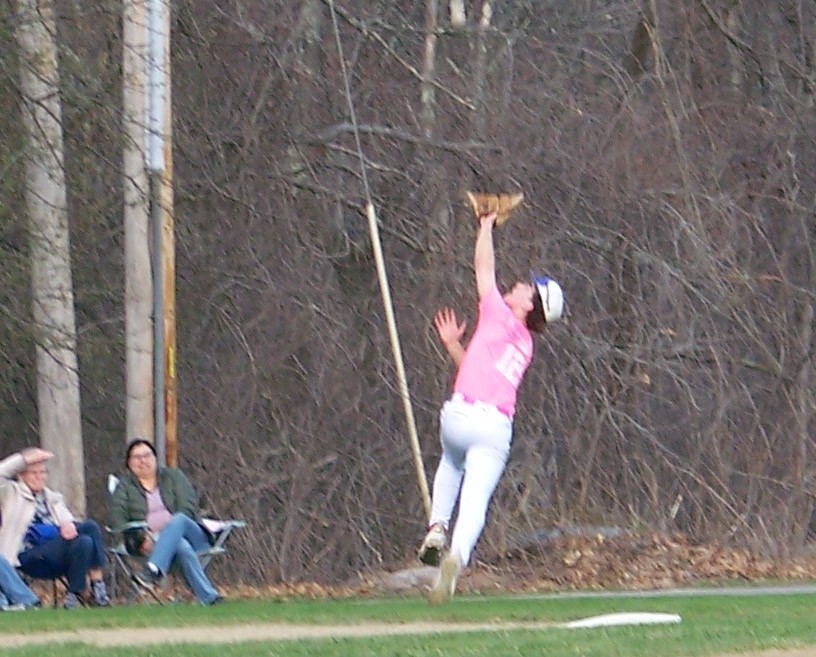 A player with his mitt in the air chases after an incoming ball.