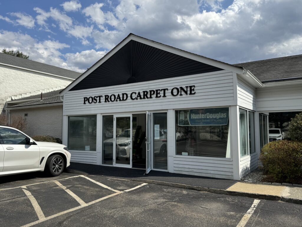 A white building with a sign that says Post Road Carpet One.