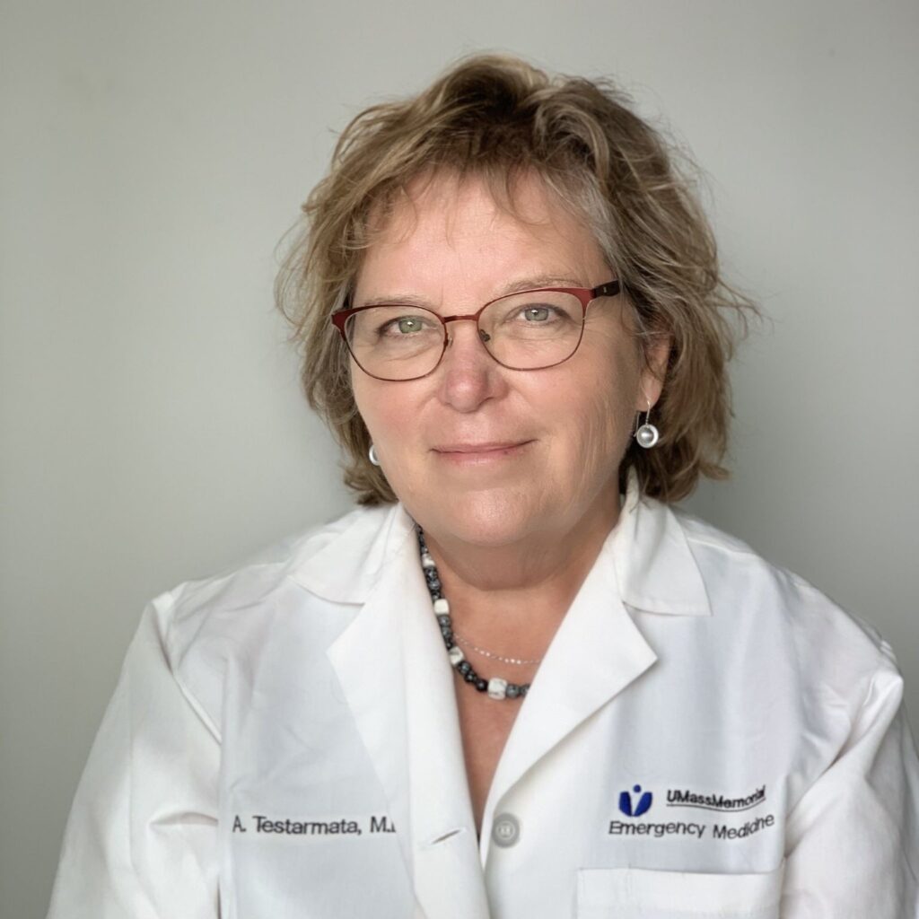 A woman with blondish hair and glasses wearing a UMassMadical jacket with her name embroidered; A Testarmata MD.