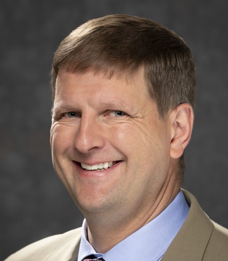 A smiling man with short brown hair.