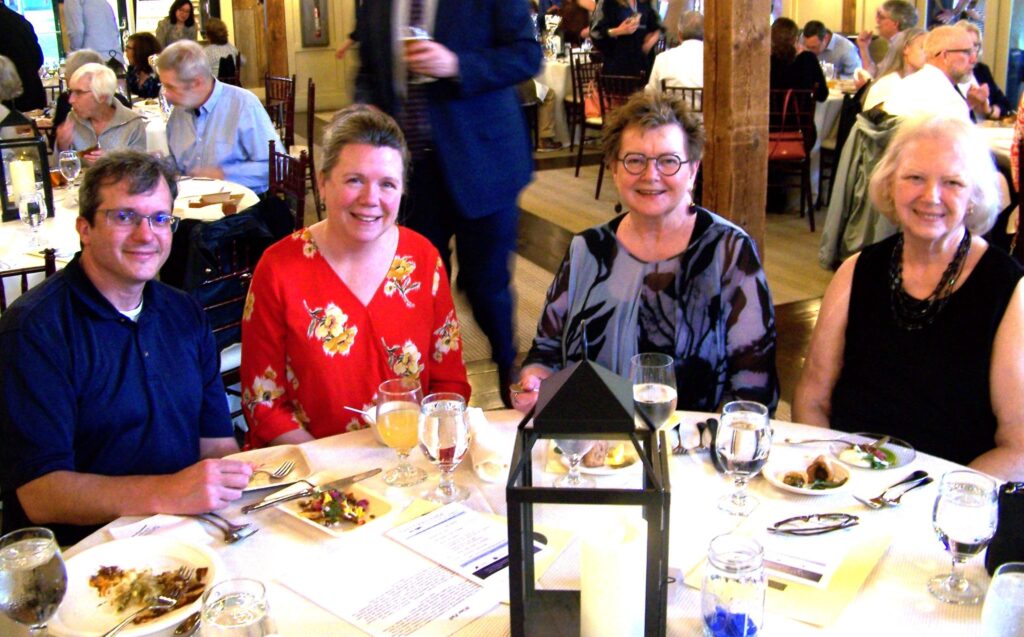 Four smiling people sitting at a table with many small plates.