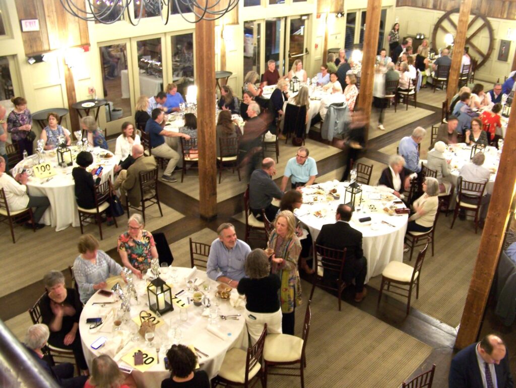 A birds-eye view of several tables of eight. Many seats are empty while people are getting new treats.