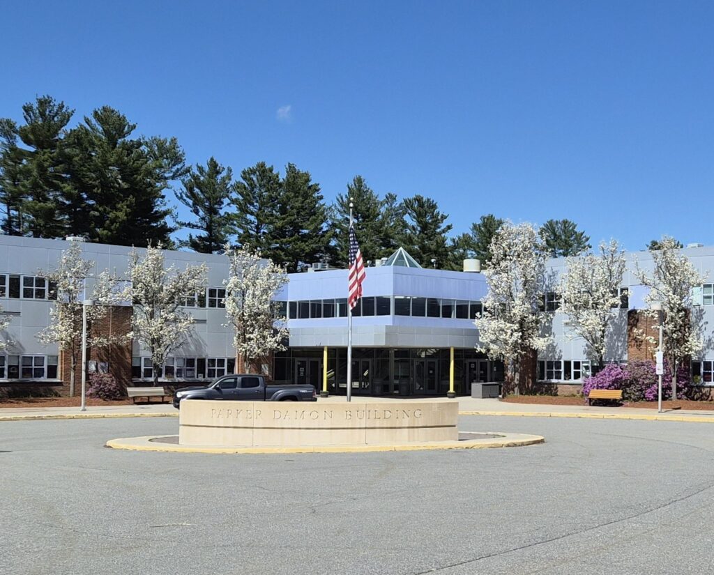 A large, silvery building with a flagpole in the front. A concrete barrier says Parker Damon Building.