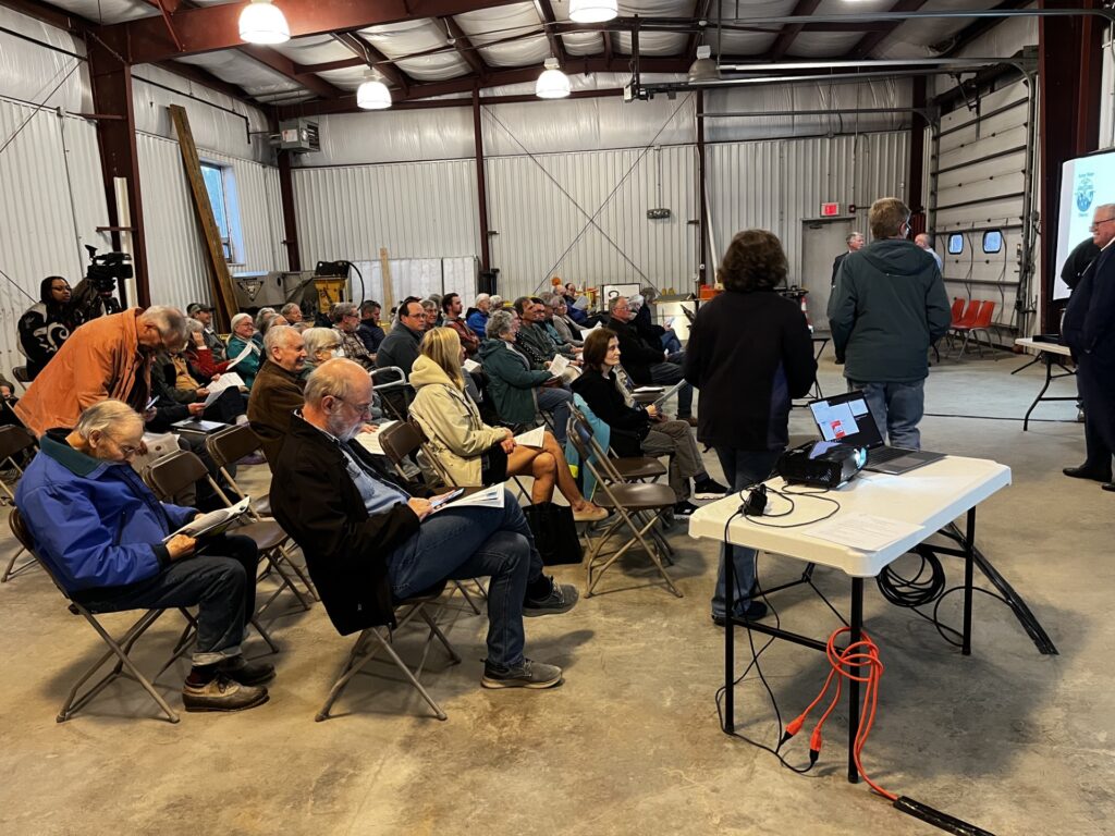 A group of people, still in their jackets, sit in a large garage. It wasn't elegant, but it worked.