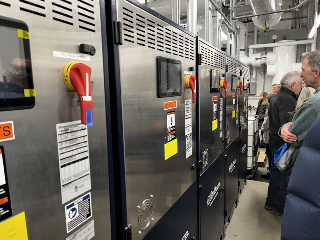 A wall of large metal boxes with red levers amd screems/