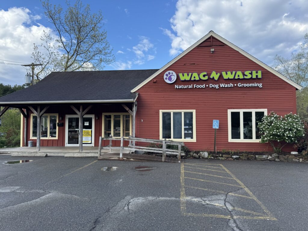 A reddish brown wooden building with a ramp in front. The Wag 'N' Wash logo is still on the the font.