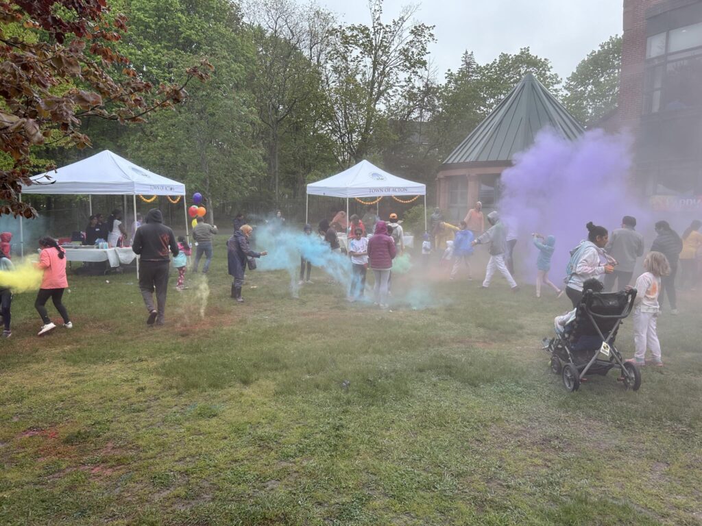 The lawn at Acton Memorial Library.A couple of tents are in the backgroud. In the foreground are bright clouds of color and people of all ages running around.