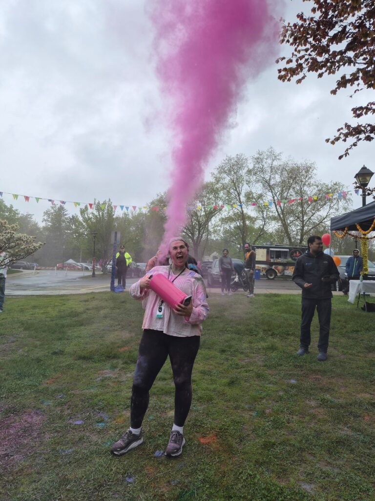 A woman shoots a cannister of purple color into the air. She seems to be screaming (with joy, perhaps).