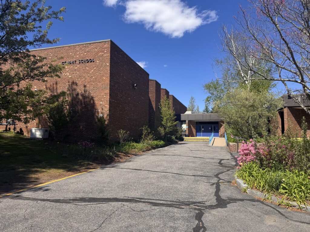 A brick school building in the sun. Blue doors greet the students.