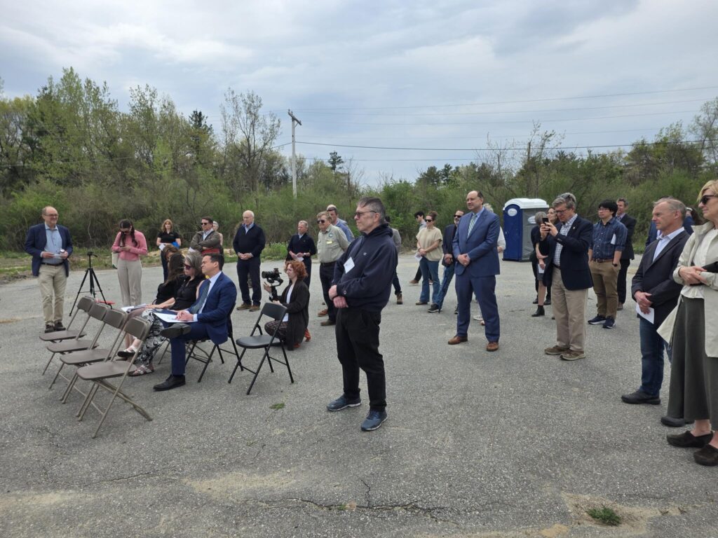 30 or so people stand and sit in a parking lot.