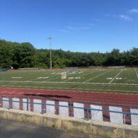 A sports field with the AB logo in the middle and a cinder track in the forefront.