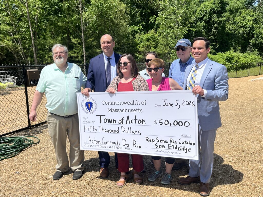 A group of smiling people lined up behind an oversized check for $50.000.