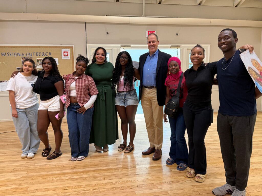A group of high school kids stand proudly with two adults.