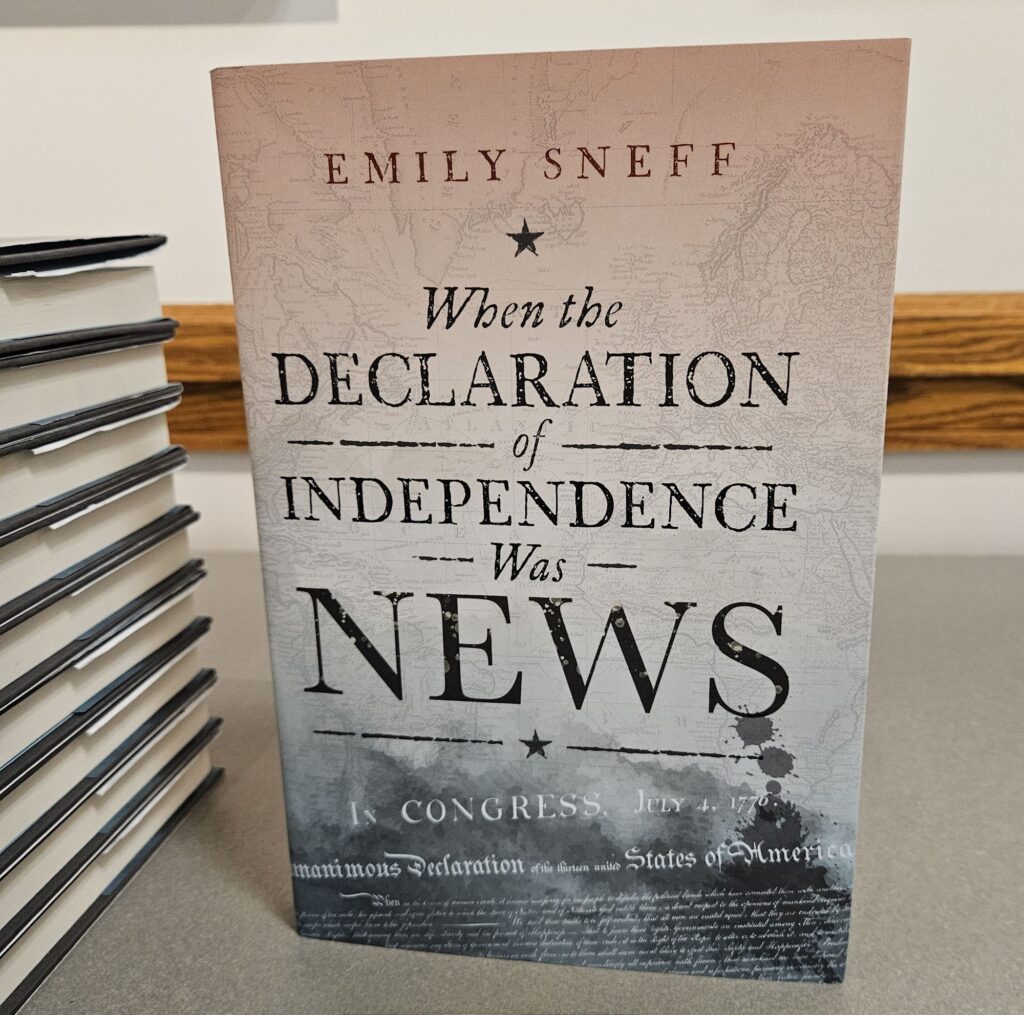 A book entitled "When the Declaration of Independence was News" by author Emily Sneff standing upright on a table.