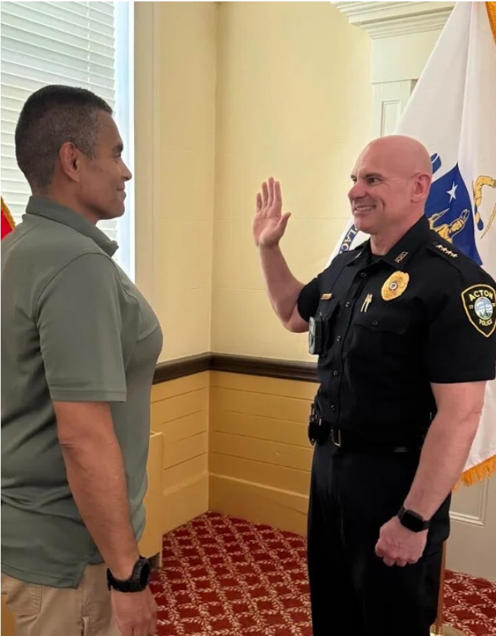 Town Clerk Leo Mercado swearing in Police Chief Douglas Sturniolo in uniform with hands raised.